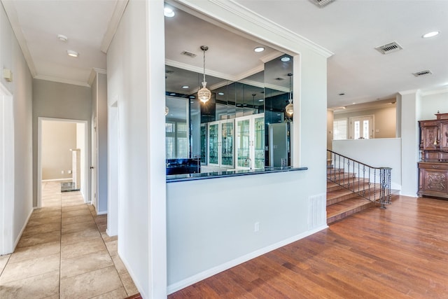 corridor with baseboards, wood finished floors, visible vents, and crown molding