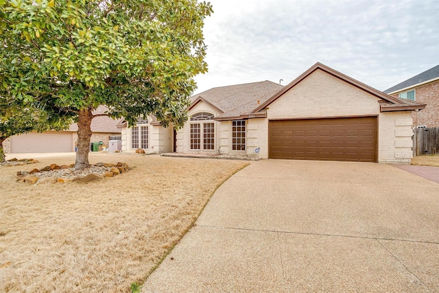 ranch-style home with brick siding, an attached garage, concrete driveway, and fence