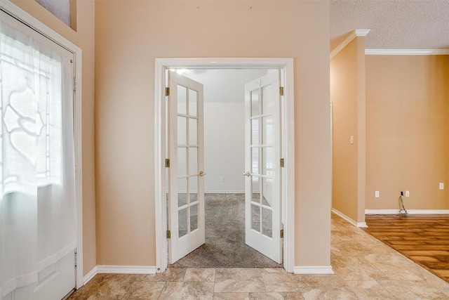 foyer entrance with french doors, a textured ceiling, crown molding, and baseboards