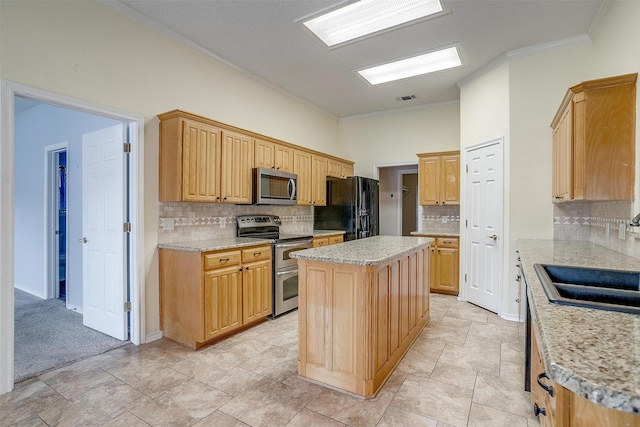 kitchen with visible vents, ornamental molding, a sink, appliances with stainless steel finishes, and a center island