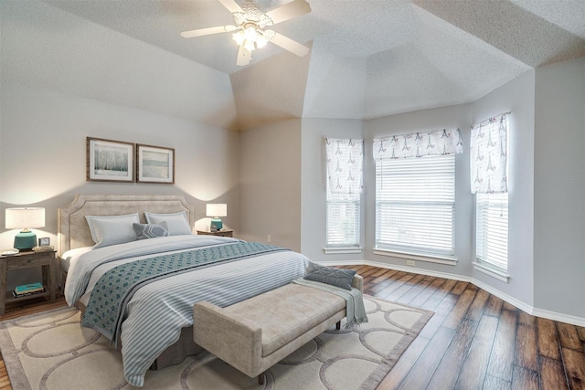 bedroom featuring lofted ceiling, hardwood / wood-style flooring, a textured ceiling, baseboards, and ceiling fan