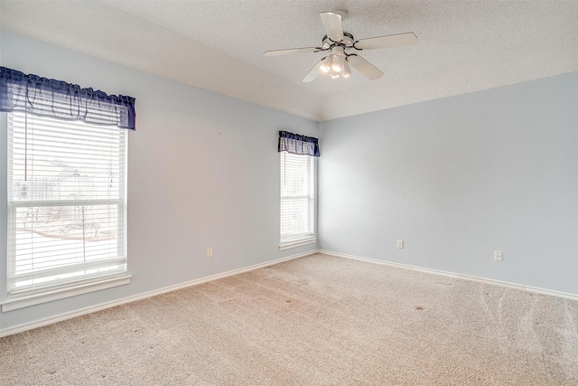 carpeted spare room with a textured ceiling, vaulted ceiling, baseboards, and ceiling fan