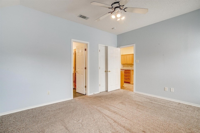 unfurnished bedroom featuring connected bathroom, light colored carpet, visible vents, and baseboards