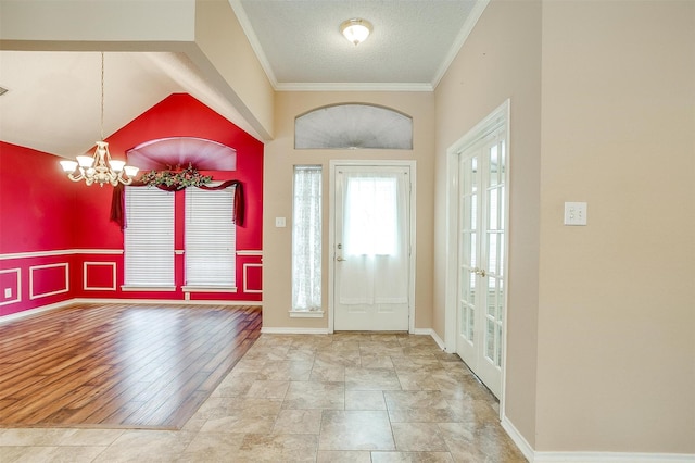 foyer with baseboards, an inviting chandelier, french doors, a textured ceiling, and crown molding