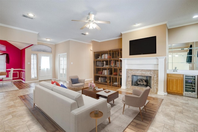 living area featuring ceiling fan, a premium fireplace, visible vents, and beverage cooler