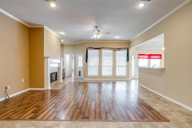 unfurnished living room with baseboards, ornamental molding, a premium fireplace, wood finished floors, and a ceiling fan