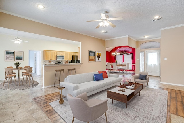 living area with visible vents, crown molding, baseboards, ceiling fan with notable chandelier, and a textured ceiling