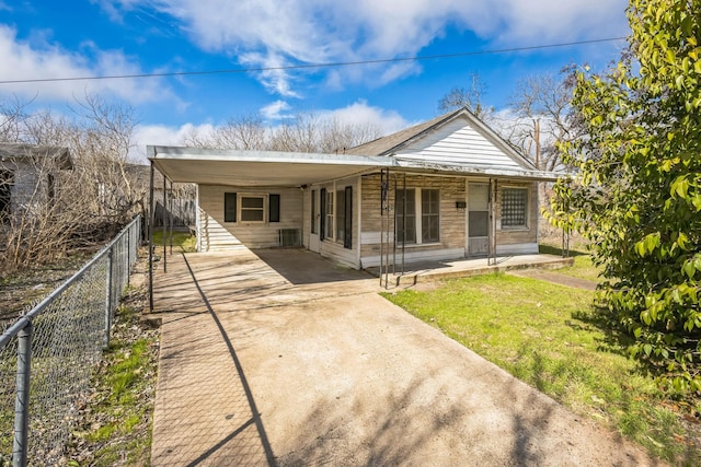 view of front facade featuring driveway, an attached carport, a front yard, and fence