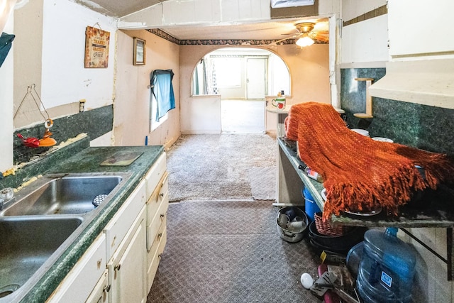 kitchen with vaulted ceiling, carpet floors, a sink, and white cabinetry