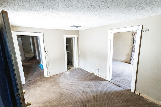 unfurnished bedroom featuring carpet floors, baseboards, visible vents, and a textured ceiling