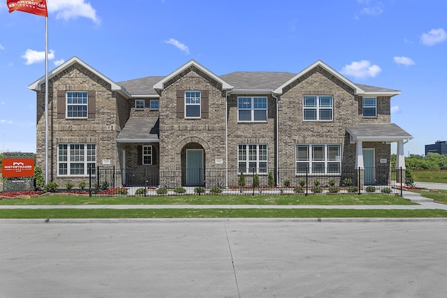 view of front of house featuring brick siding and a fenced front yard