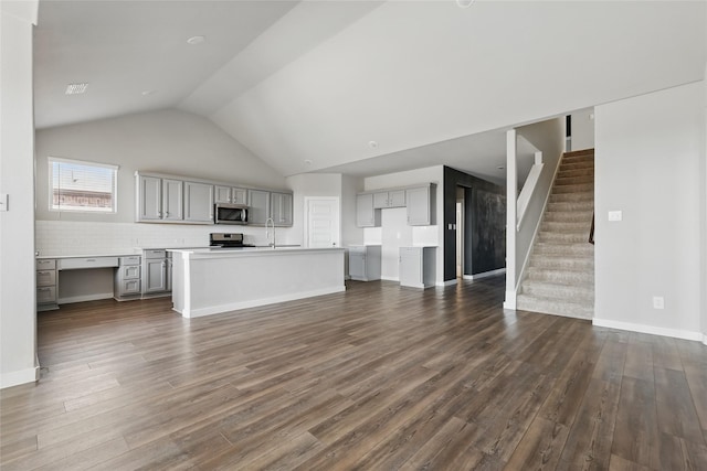 unfurnished living room featuring high vaulted ceiling, dark wood-type flooring, a sink, baseboards, and stairs