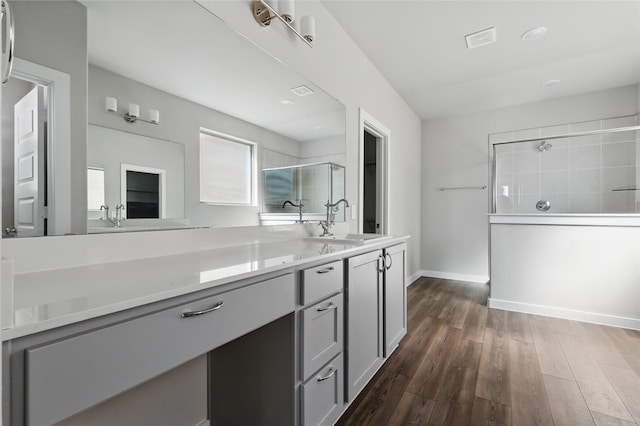 bathroom with visible vents, baseboards, tiled shower, wood finished floors, and vanity