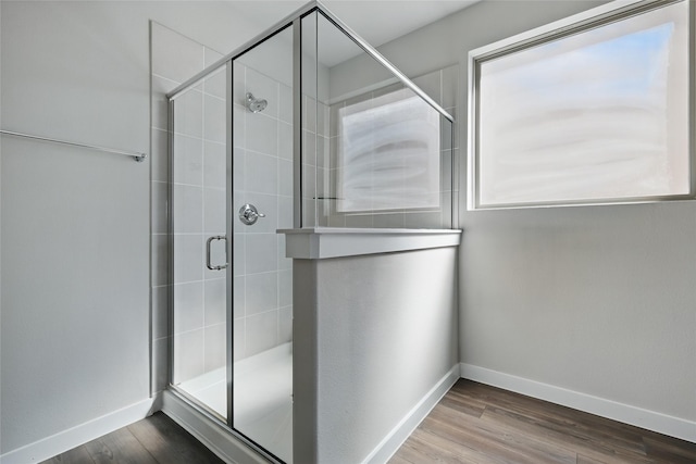 bathroom featuring wood finished floors, baseboards, and a stall shower