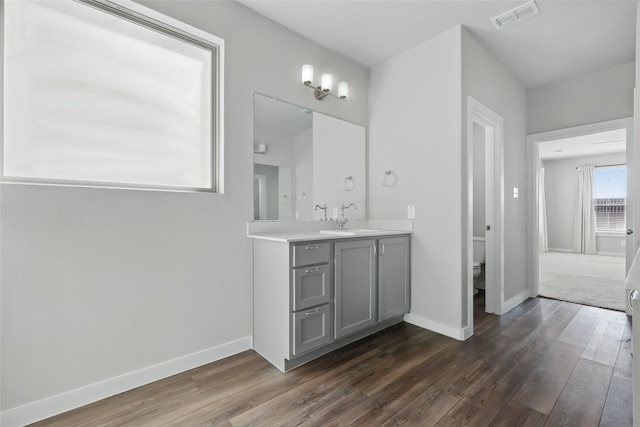 bathroom with toilet, wood finished floors, visible vents, and baseboards