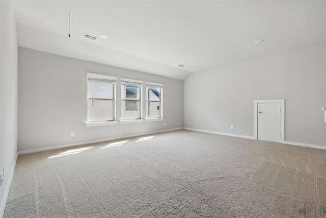 carpeted spare room featuring visible vents, baseboards, and vaulted ceiling