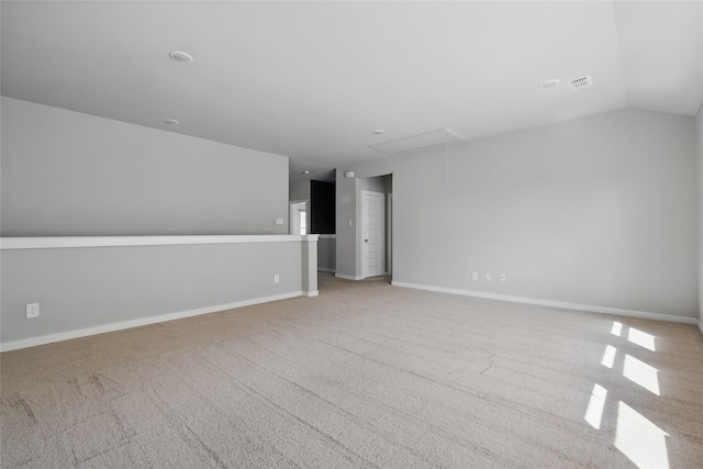 spare room featuring visible vents, lofted ceiling, baseboards, light colored carpet, and attic access