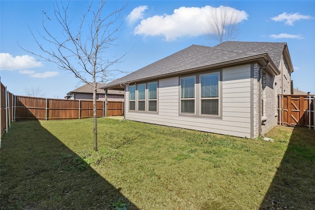 back of property with a yard, a fenced backyard, brick siding, and a shingled roof