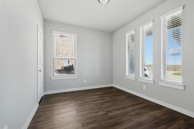 spare room featuring baseboards and dark wood-style flooring