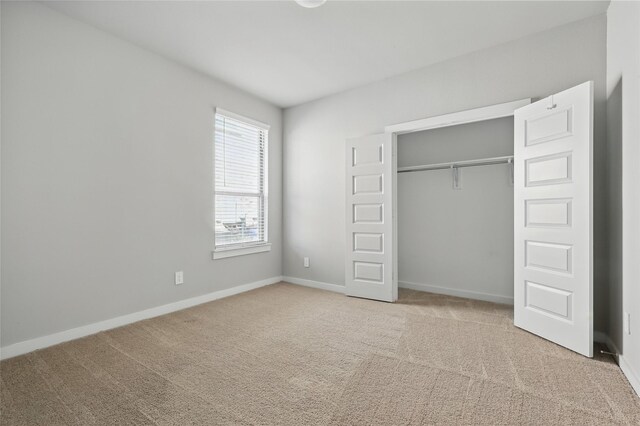 unfurnished bedroom with a closet, carpet flooring, and baseboards