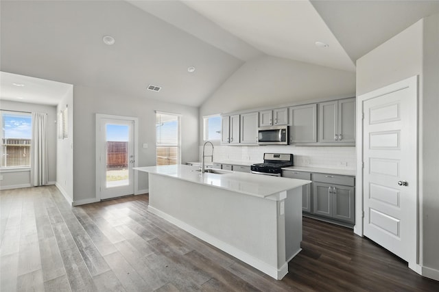 kitchen featuring visible vents, gray cabinetry, a sink, backsplash, and appliances with stainless steel finishes