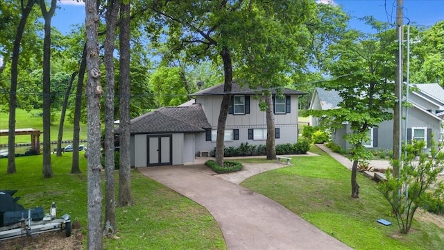 traditional-style home featuring roof with shingles, concrete driveway, and a front yard