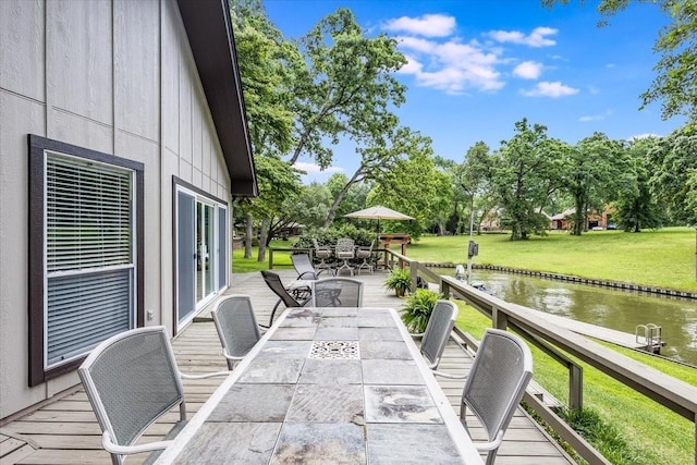 wooden terrace featuring a water view, a yard, and outdoor dining space