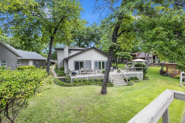 rear view of house featuring a lawn and a deck