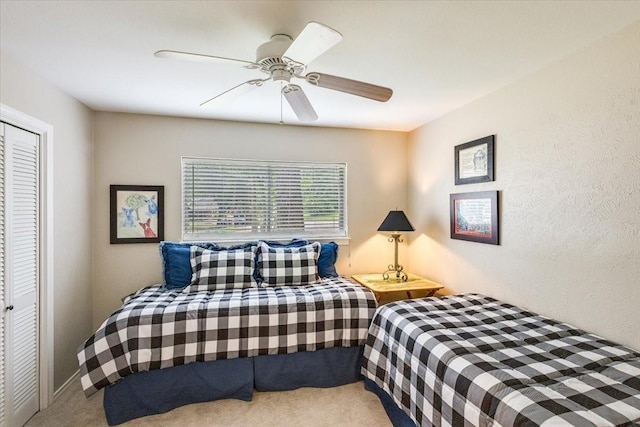 carpeted bedroom featuring a ceiling fan, a closet, and a textured wall