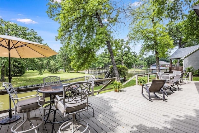 deck featuring outdoor dining area and a lawn