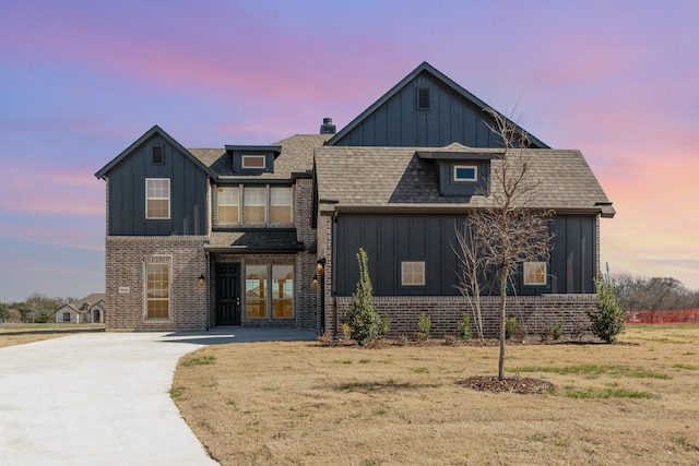 view of front of house featuring board and batten siding, brick siding, and a shingled roof