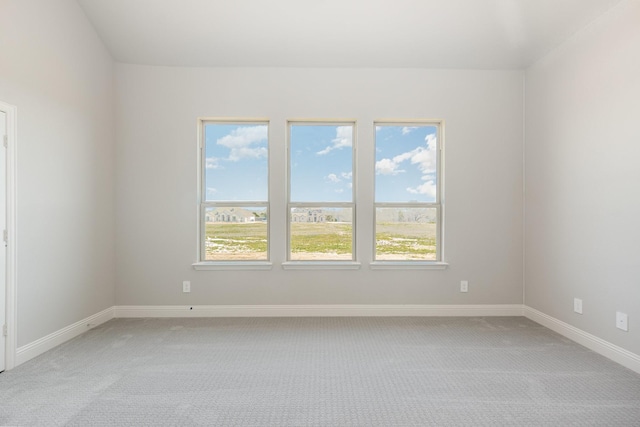 spare room with light carpet and baseboards