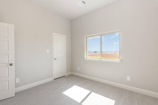 spare room with baseboards, visible vents, and light colored carpet