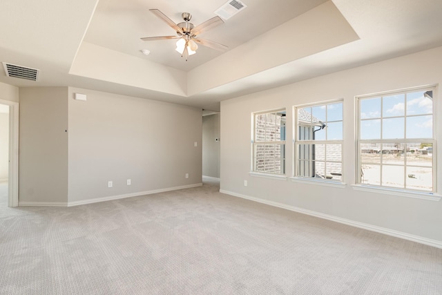 unfurnished room with a ceiling fan, visible vents, a tray ceiling, and baseboards