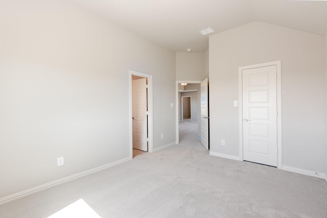 unfurnished bedroom with lofted ceiling, light carpet, and baseboards