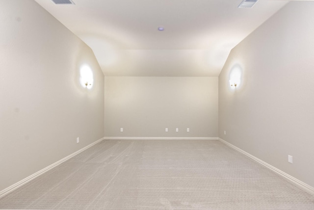 unfurnished room featuring lofted ceiling, baseboards, and light colored carpet