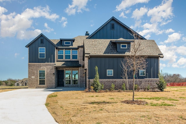 view of front facade featuring board and batten siding, a front yard, and brick siding