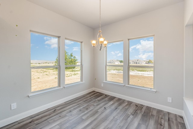 interior space with a notable chandelier, wood finished floors, and baseboards