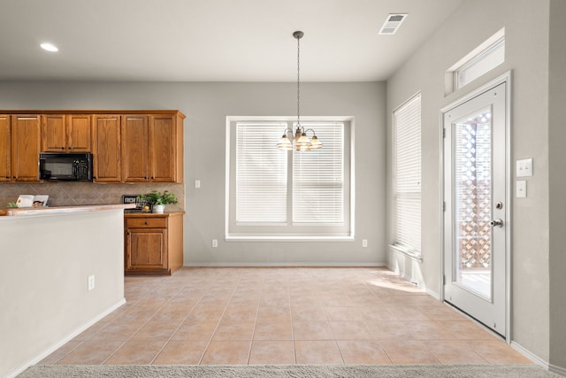 kitchen with brown cabinetry, black microwave, visible vents, and a notable chandelier