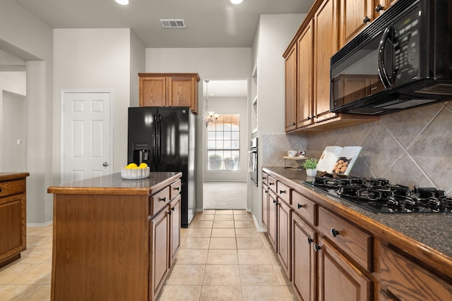 kitchen with a center island, dark countertops, visible vents, brown cabinetry, and black appliances