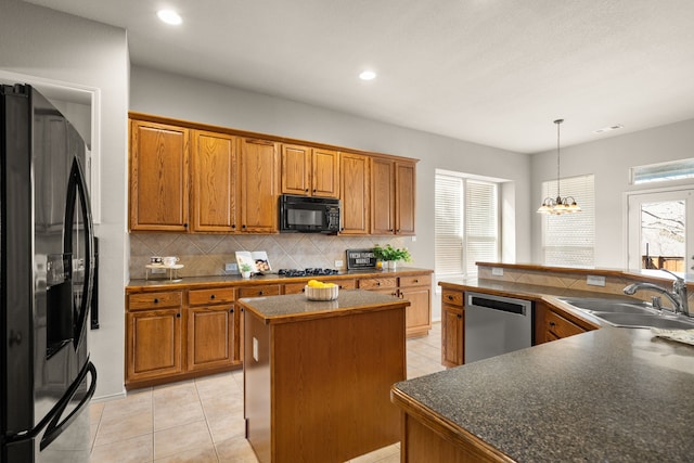 kitchen with black appliances, a kitchen island, brown cabinetry, and a sink