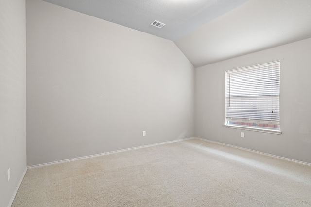 carpeted empty room featuring lofted ceiling, baseboards, and visible vents