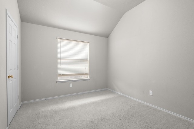 carpeted empty room with vaulted ceiling and baseboards