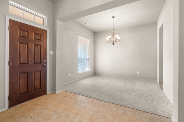 foyer entrance with light tile patterned flooring, light carpet, visible vents, baseboards, and an inviting chandelier