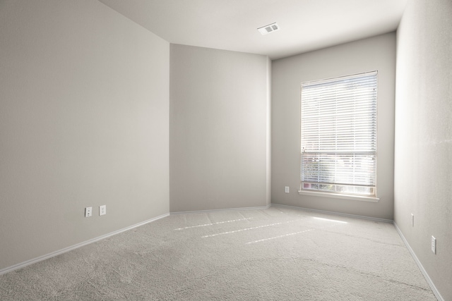 carpeted spare room featuring baseboards and visible vents