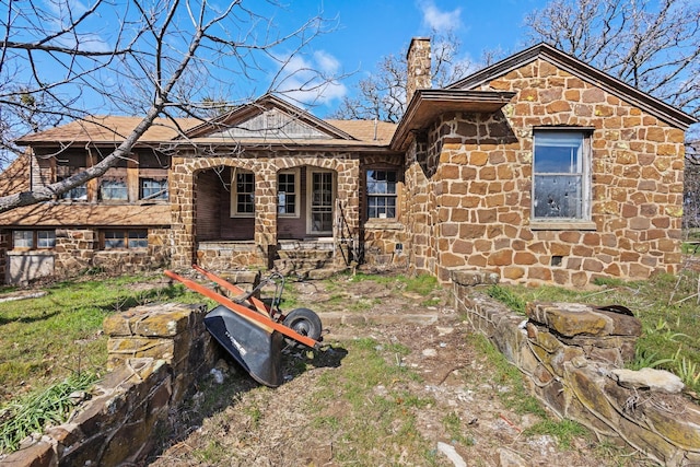 exterior space with covered porch, stone siding, and a chimney