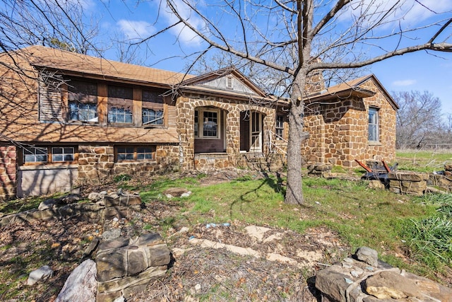 view of front of house with stone siding and a chimney