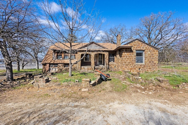 view of front facade featuring stone siding and a chimney