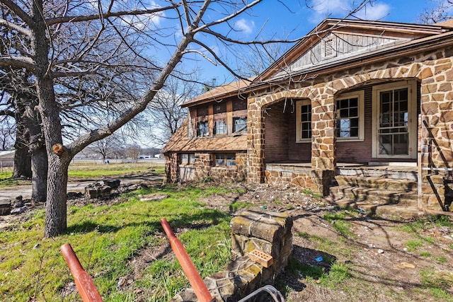 view of side of home featuring a porch and stone siding