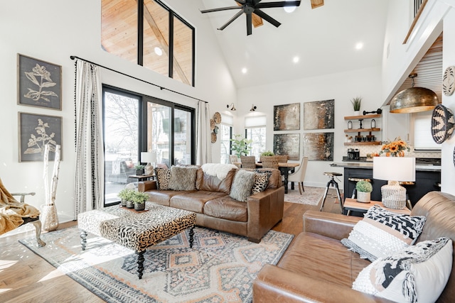 living area with high vaulted ceiling, ceiling fan, baseboards, and wood finished floors